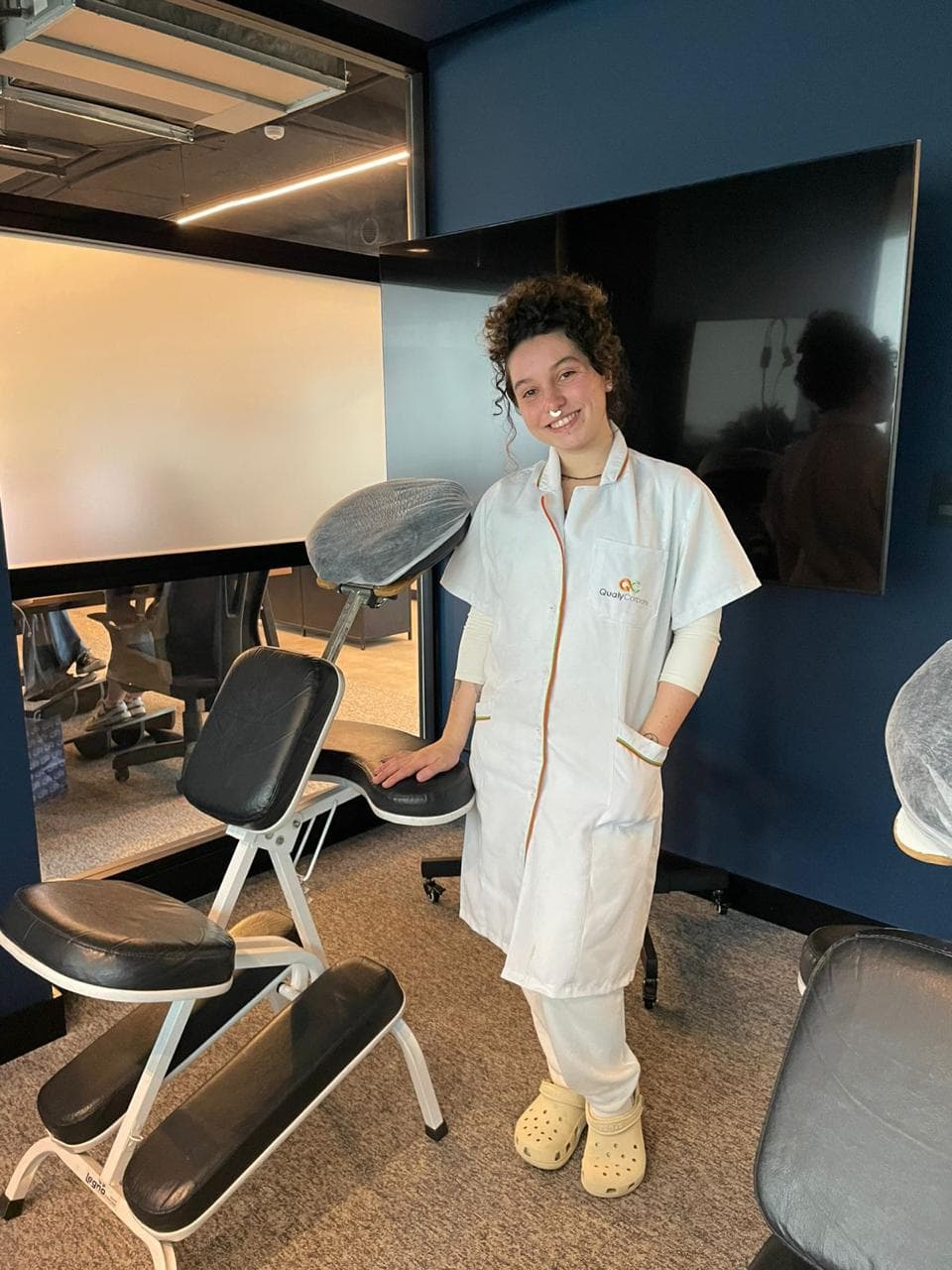 Laura com a cadeira de quick massage em uma empresa