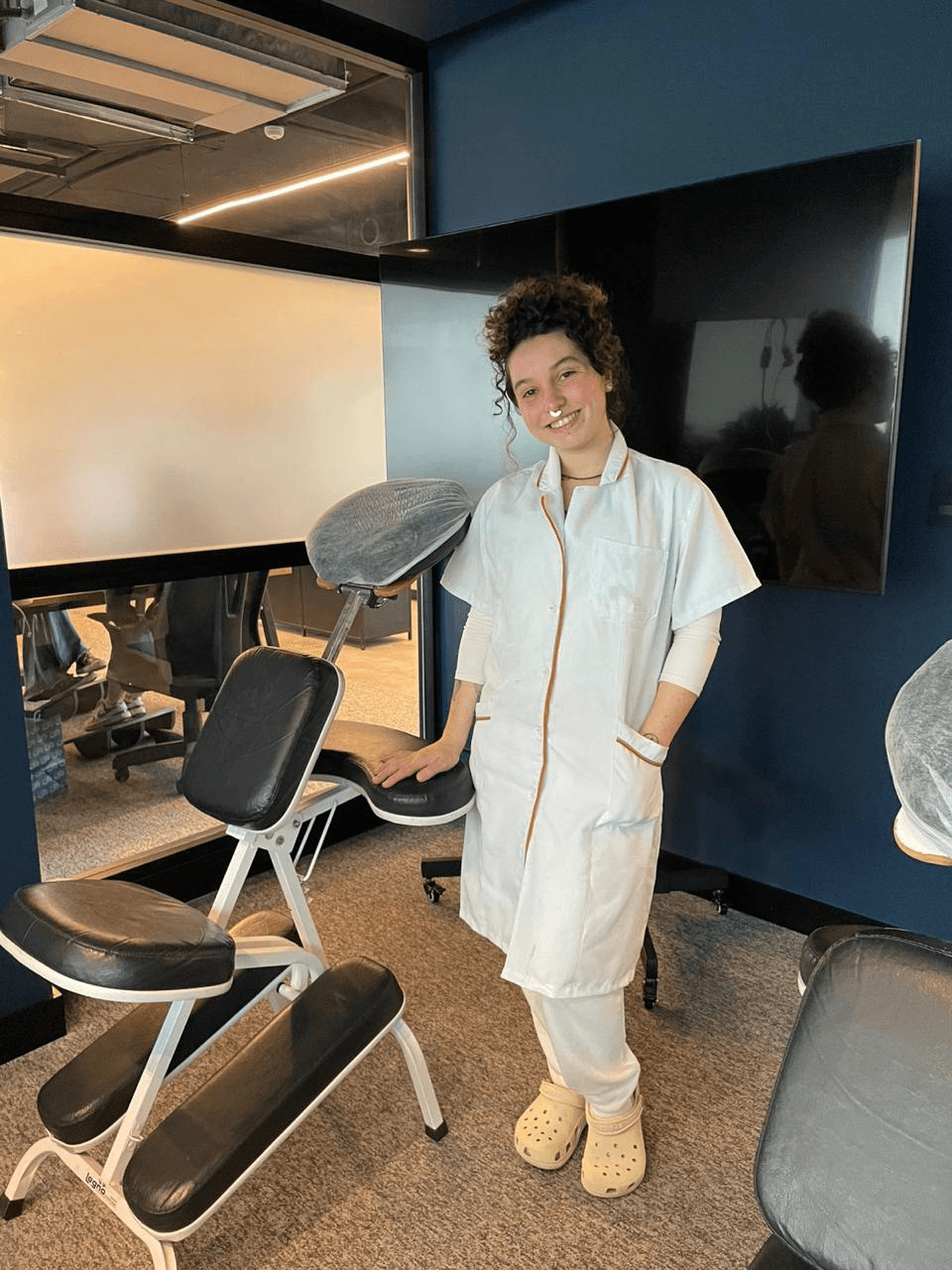 Laura com a cadeira de quick massage em uma empresa